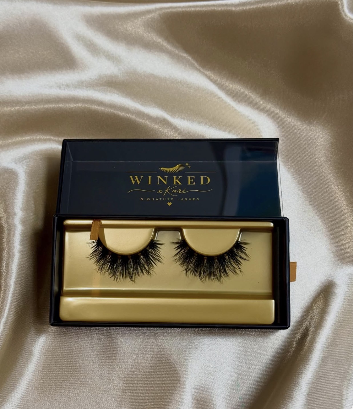 Honey strip lashes in the black and gold Winked x Kari box on champagne satin